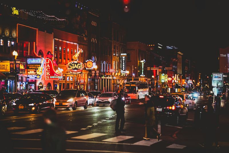 Image is of Broadway in Downtown Nashville, TN at night with lots of neon lights,