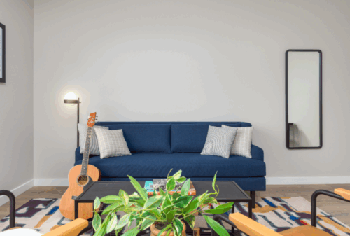 Image is of a blue couch and a wooden guitar leaning up against it in the living room of one of the suites in Motif on Music Row